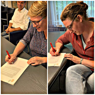 Foto van Judit en Marjan die een handtekening zetten bij de notaris voor de Stichting